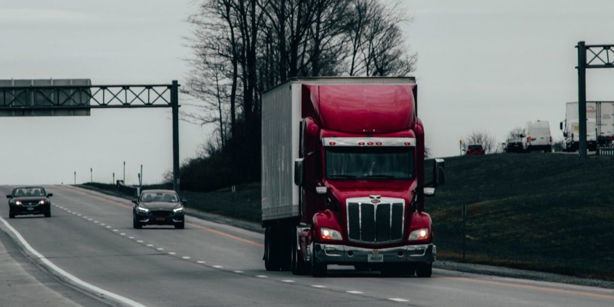 Photographie d'un camion de transport rouge sur une autoroute